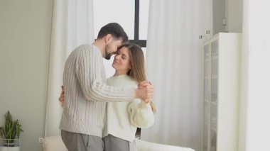 Genç çift evde vals yapar ve sevinir, karı koca birlikte gülümser ve kutlarlar.