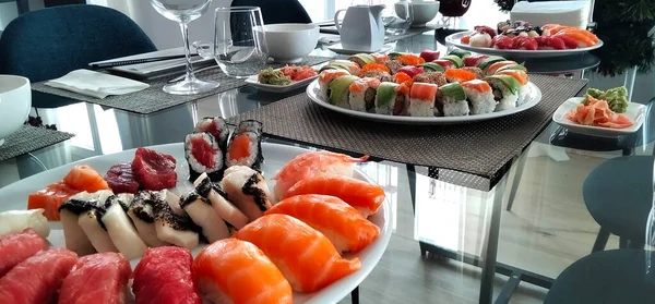 Kutlama için cam masa. Japon suşi yemeği. Maki, nigiri ve sashimi ile ton balığı, somon, karides ve avokado.