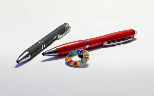 2030 Agenda Sustainable Development Wheel pin and two pens over white background. Corporate social responsibility. Sustainable Development for a better world