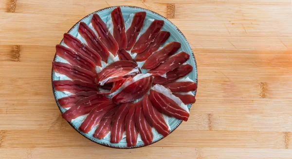 Ahşap bir masanın üzerinde duran bir tabak iberik jambon. İspanyol geleneksel jamonu