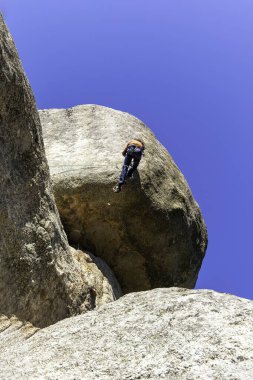 Madrid, Torrelodones 'da granit bir çıkıntıya tırmanan genç bir yetişkin. Kaya tırmanışı. Ekstrem spor kavramı