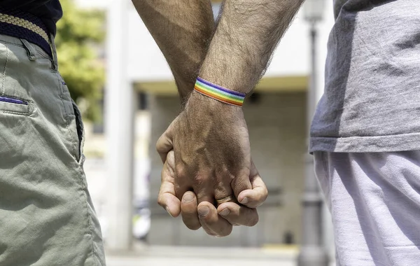 片方の手首に虹色のブレスレットで手を握っている男性のゲイカップルのクローズアップ プライド コンセプト — ストック写真