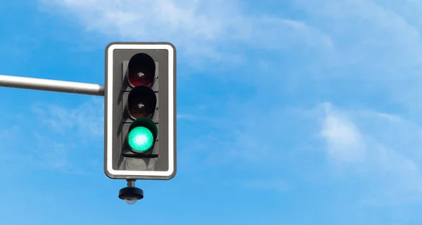 Traffic light on green, with blue sky and clouds on the background. Copy space