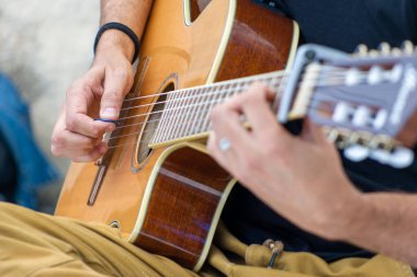 Açık havada akustik gitar çalan birine yakın çekim. Seçici odak