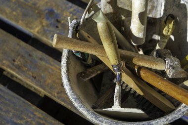 Kullanılmış inşaat aletleri, açık havada bir kovada depolanmış. Yukarıdan bak, güneş ışığı manzarayı aydınlatıyor..