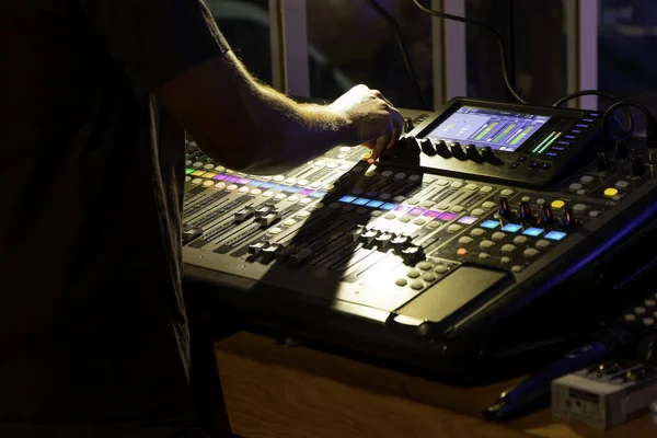 unrecognizable sound technician adjusting levels on a multitrack mixing console in the control room during an event
