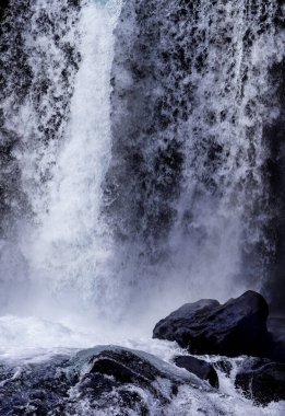Önünde kaya olan bir şelale. Su beyaz ve kaya siyah.
