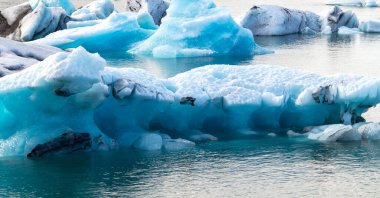 Okyanusta büyük bir buz parçası yüzüyor. Buzun etrafı suyla çevrili ve kısmen sular altında. Sahne sakin ve sakin, mavi buz berrak suya karşı koyuyor.
