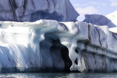 Üzerinde mavi bir delik olan büyük bir buz bloğu. Delik buzla çevrili ve bir tünel oluşturuyor.
