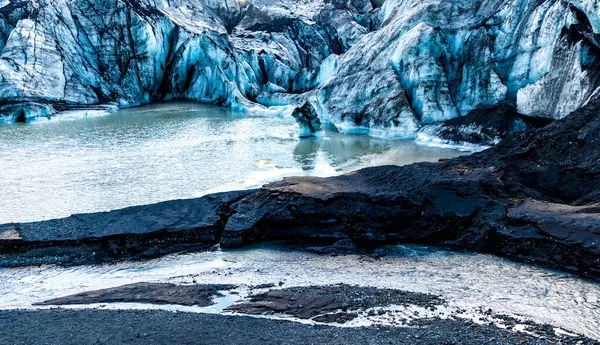 Ortasında küçük bir su kütlesi olan donmuş bir göl. Solheimajokull Buzulu, İzlanda. Su bulanık ve buz kalın.