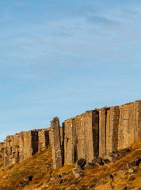 Arka planda mavi gökyüzü olan büyük bir kaya oluşumu. Kayalar uzun ve gökyüzüne uzanıyor gibi görünüyor. Boşluğu Kopyala