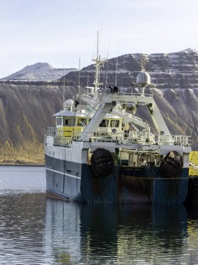 Rıhtıma büyük bir tekne yanaştı. Tekne büyük ve içinde bir sürü ekipman var. Su sakin ve gökyüzü berrak.