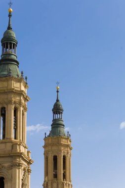 Yeşil kuleleri ve altın tepeleri olan iki uzun kule. Gökyüzü açık ve mavi. Zaragoza 'daki El Pilar Bazilikasının ayrıntıları