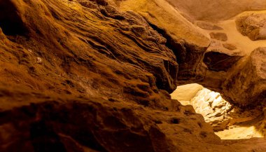 Ortasında küçük bir delik olan bir mağara. Mağara karanlık ve ışık açıklıktan parlıyor.
