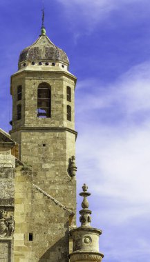 Çan kulesi ve tepesinde kubbesi olan yüksek bir bina. Bina eski ve çok fazla detayı var. Gökyüzü mavi ve bazı bulutlar var. İspanya, Ubeda 'da Kurtarıcının Kutsal Şapeli