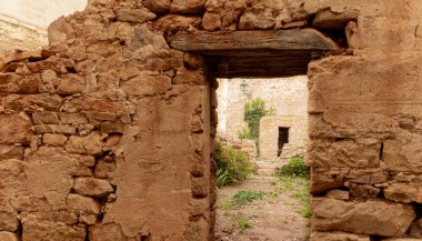 Doğa eski bir evi ele geçiriyor, kapısı açık taş bir bina. Ev çatısını kaybetti ve içinde bitkiler ve çiçekler büyüyor..