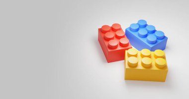 Beyaz arka planda üç farklı renkli lego bloğu. Renkler kırmızı, sarı ve mavi.