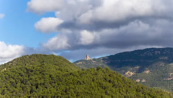Arka planda bulutlu bir gökyüzü olan bir dağ sırası. Bulutlar alçak ve gri ve dağ zirveleri uzaktan görülebilir. Huzurlu ve huzurlu bir sahne.