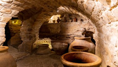 Bir sürü vazosu ve taş tavanı olan bir oda. Vazolar farklı boyutlarda ve şekillerde, ve bir derinlik ve boyut hissi yaratacak şekilde sıralanmış.