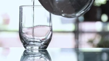 Suyla dolu bir bardak. Su berrak ve küçük kabarcıklar oluşturuyor. Camın yüzeyinde küçük lekeler olan modern bir yaşlanma tarzı vardır.