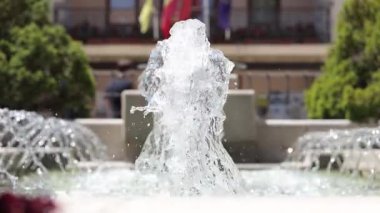 Havaya su fışkırtan büyük bir çeşme. Su temiz ve çeşme ağaçlarla çevrili.