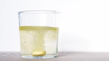 Bir bardak suda çözünen coşkun bir tablet, turuncu renkli bir ilaçla sonuçlanır.