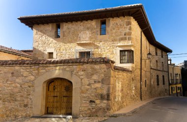 Ahşap kapılı büyük bir taş bina. Bina eski ve kırsal bir görünüme sahip.