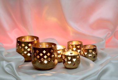 Parlak tekstil arka planında altı küçük mum feneri.