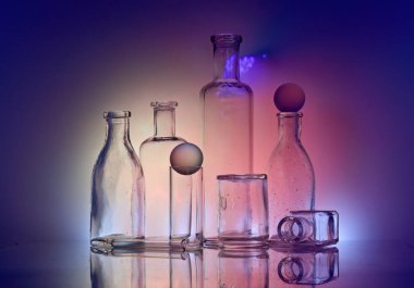 Yansıtıcı yüzeyde eski cam şişeler ve kavanoz ve renkli arka aydınlatma