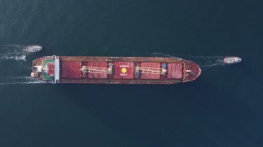 Römorkör teknesinin havadan görünüşü büyük bir kargo gemisine yardım ediyor. Büyük gemiye römorkör eşlik ediyor..