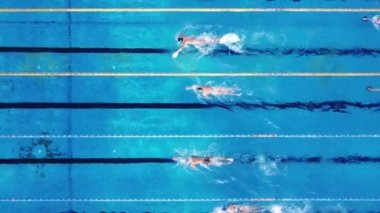 Yüzücülerden oluşan bir grup, havuz üstü havuz manzaralı bir yerde eğitim görüyor.