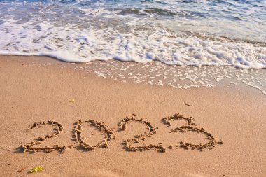 2023 yılı güneşli bir günde kumlu sahil denizinde çizim yaparak geçti.