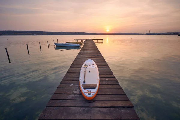 保加利亚瓦尔纳市日落时分 在湖面的木制防波堤上的Sup板 — 图库照片