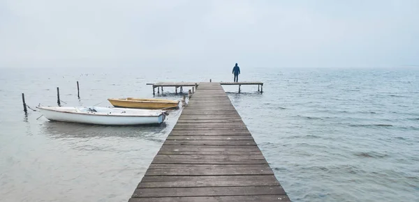 雾蒙蒙的早晨 站在湖边的木制码头或码头上的人 — 图库照片