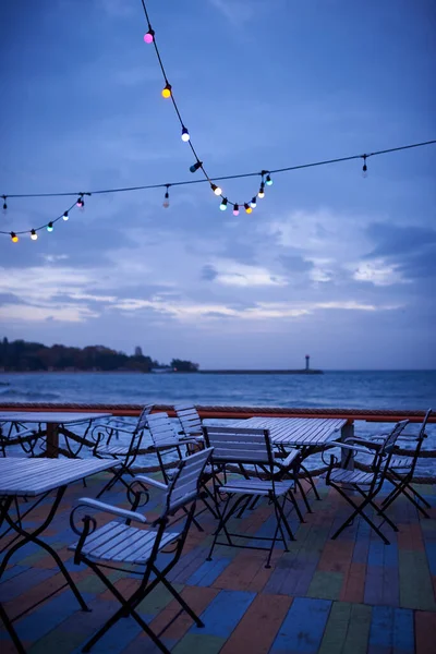 Summer empty outdoor cafe on the seashore at sunrise or sunset