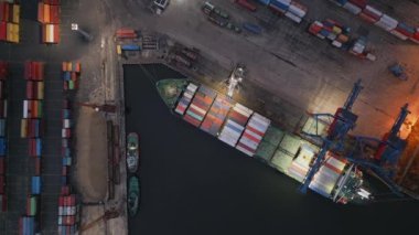 Konteynır gemisi, akşam havadan aşağıya İHA görünümünde limanda boşaltılıyor.