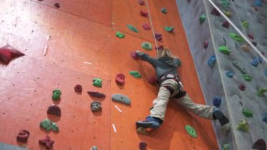 Sekiz yaşında bir çocuk koridordaki tırmanma yapay duvarına tırmanıyor..