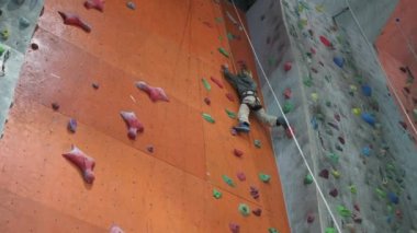 Sekiz yaşında bir çocuk koridordaki tırmanma yapay duvarına tırmanıyor..