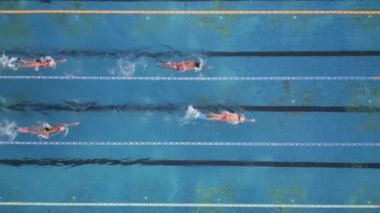 Bir grup yüzücü açık havuz manzaralı bir yerde antrenman yapıyor.