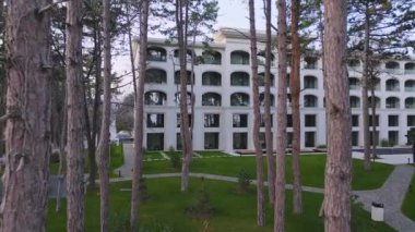 İnsansız hava aracı güzel bir çam parkından lüks bir otelin cephesine uçuyor.