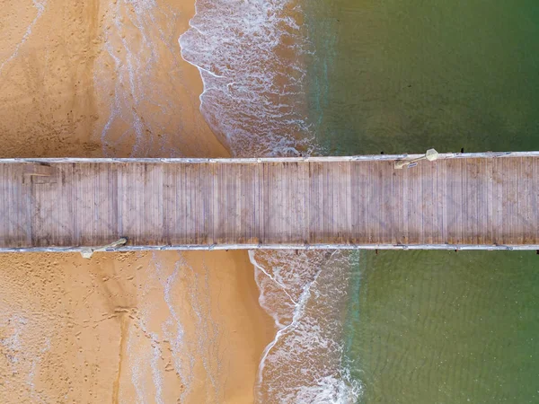 Aerial top down view of a wooden deserted pier in the sea