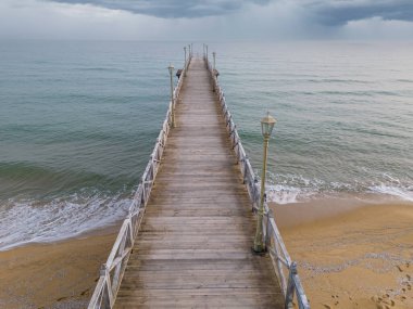 Denize doğru uzanan ıssız, ahşap bir iskele boyunca uçuyor.
