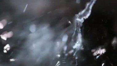 Kaynayan su, siyah arkaplanda buharla sıçrar.