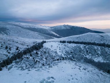 Kar, gün batımında dağları kaplamıştı. Öndeki hava manzaralı dolambaçlı bir yol vardı.