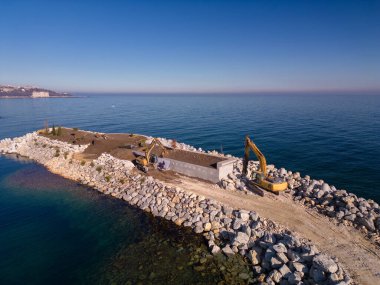Ağır inşaat ekipmanları dalgakıran inşa ediyor. Dalgakıran denizde yapım aşamasında. Havadan üst görünüm