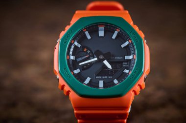 Orange bright wrist watch on wooden background closeup