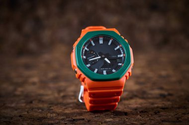 Orange bright wrist watch on wooden background closeup