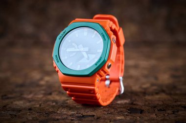 Orange bright wrist watch on wooden background closeup