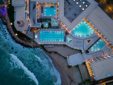 Aerial top view of several pools in the spa center on a sea coast at night