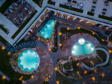 Aerial top view of several pools in the spa center on a sea coast at night